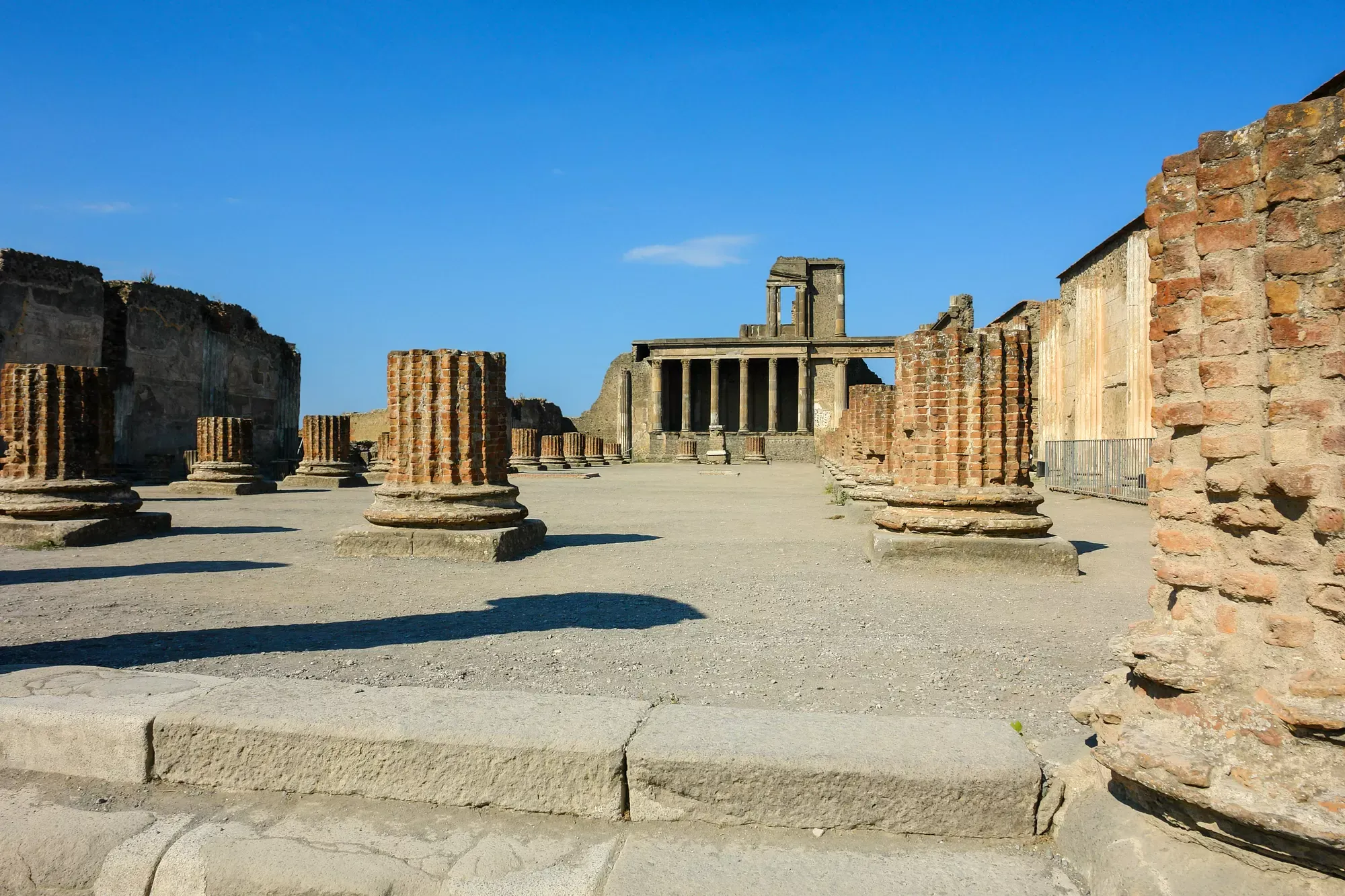 Row of classical Roman columns among Pompeii excavation ruins